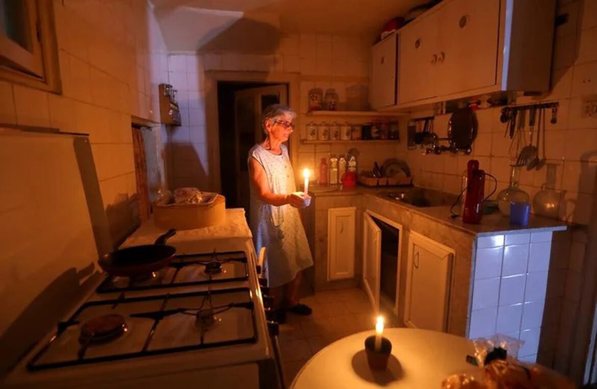 CREDIT REUTERS – MOHAMED AZAKIR__Samira Hanna uses candles to light her kitchen during a power cut in Beirut